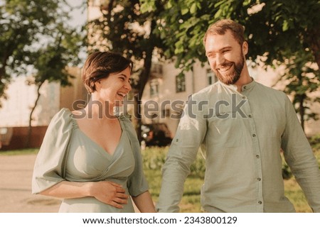 Pregnant couple hugging in nature. Husband with his pregnant wife walking on the background of the city and the park. Happy family concept photo. No focus blurred and noise effect
