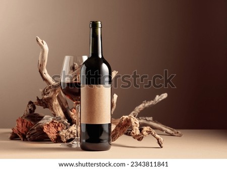 Bottle and glass of red wine with a composition of old wood. Minimalistic composition on a beige background for product branding, identity, and packaging. Copy space. Royalty-Free Stock Photo #2343811841