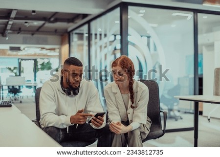 In a modern office African American young businessman and his businesswoman colleague, with her striking orange hair, engage in collaborative problem-solving sessions Royalty-Free Stock Photo #2343812735