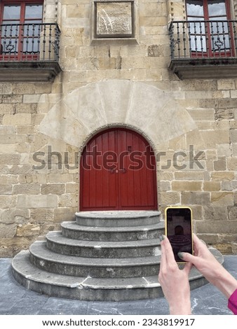 Girl takes pictures on phone of old vintage entrance doors in ancient house. Phone screen showing doors. Vertical frame.