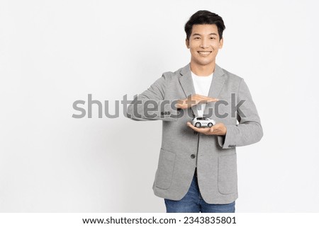 Young Asian businessman holding car model isolated on white background, Car Insurance concept