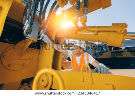Machinery tractor mechanic checks hydraulic hose system equipment on excavator. Royalty-Free Stock Photo #2343846417