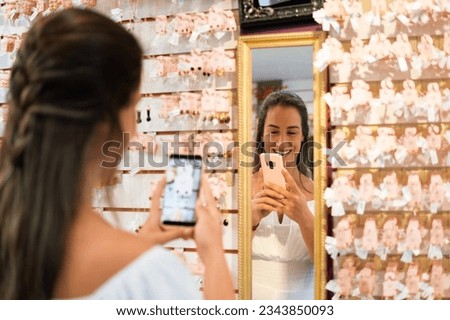 A saleswoman photographs earrings on the shelf at a neighborhood store