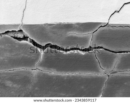Big long tortuous crack on the wall. Destructions on the wall of an old building. Copy space. Black and white photo. Selective focus. Royalty-Free Stock Photo #2343859117