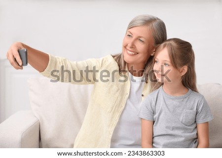 Happy grandmother taking selfie with her granddaughter at home