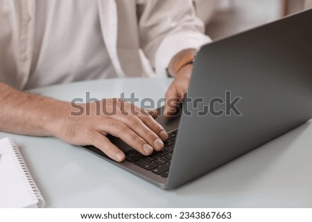 Man using modern laptop at table in cafe, closeup