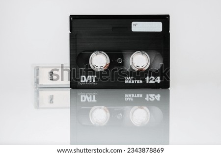 Front view of a DAT (digital audio tape) cassette with box isolated on white background with reflection