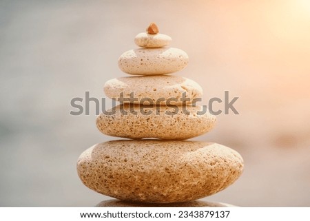 Pyramid stones on seashore with warm sunset on sea background for perfect holiday. Pebble beach and calm sea create a serene travel destination. concepts of happy vacation, meditation spa and calmness