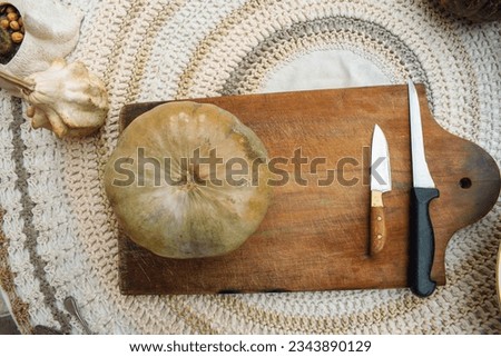 halloween background, a pumpkin and two knives on a wooden cutting board, on a table with copy space