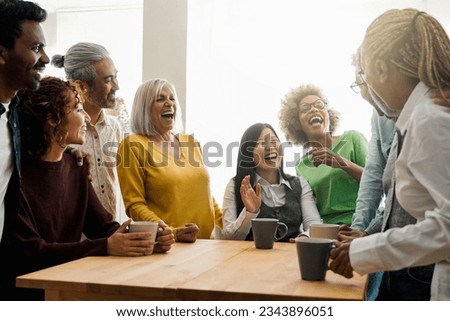Happy multiethnic people drinking tea during lunch break at work - Group of multi-generational friends having fun laughing together - Soft focus on Asian senior man face Royalty-Free Stock Photo #2343896051