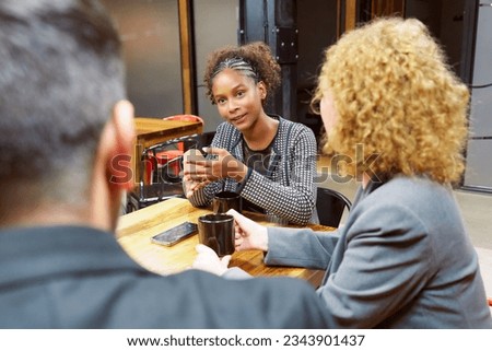 portrait young black woman sitting in meeting with group of business people talking Royalty-Free Stock Photo #2343901437