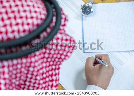 Arabic man holding pen while reading the contract before signing it