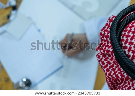 Arabic man holding pen while reading the contract before signing it