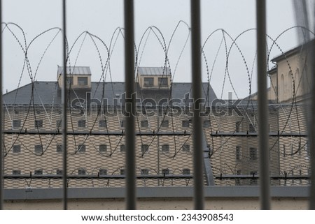 a prison window with bars and razor wire in front of it Royalty-Free Stock Photo #2343908543