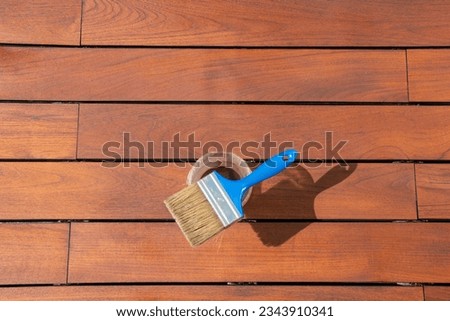 Teak wood deck renovation treatment and maintenance concept, paint brush on the bucket with oil, staining wooden decking