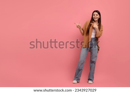 Nice Offer. Happy Smiling Teen Girl Pointing Aside At Copy Space With Two Hands, Cheerful Female Teenager Demonstrating Free Place For Advertisement While Standing On Pink Background, Full Length Royalty-Free Stock Photo #2343927029