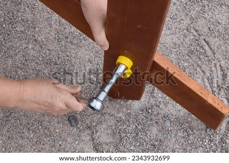 Tightening fasteners with ratchet wrench while assembling outdoor furniture. Royalty-Free Stock Photo #2343932699