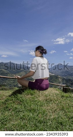 Latin woman in lotus position on green grass on a sunny day. Practice yoga.Training and meditation outdoors in summer. Wellness and Mental Health