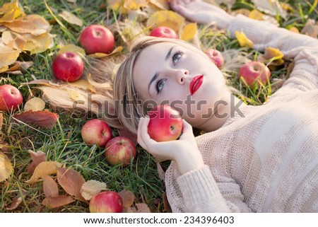 Girl with the apple is lying on the grass
