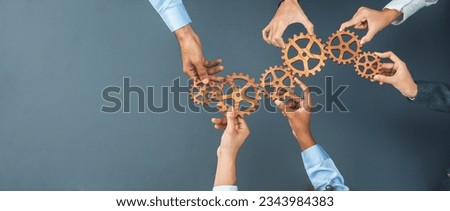 Panoramic shot top view of business people holding cog wheel as unity and teamwork in corporate workplace concept. Office worker colleague with symbol of visionary system for business success. Concord Royalty-Free Stock Photo #2343984383