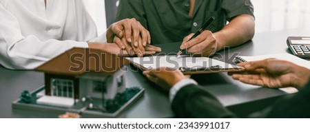 Panorama view of married couple signing house loan contract with real estate agent. Client customer purchasing new home, sealing the deal with signatures after reviewing terms and agreements. Prodigy Royalty-Free Stock Photo #2343991017