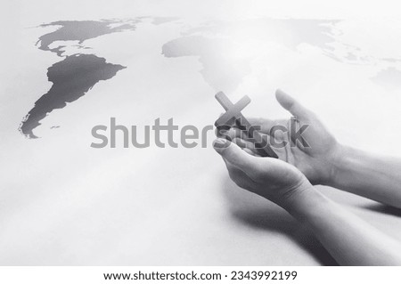 Christian holding the Holy Cross of Jesus Christ in his hand and praying for world missions, evangelism and world map background
