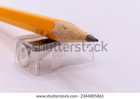 yellow pencil up top a clear pencil sharpener on a white background 