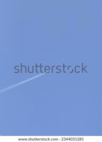 Vertical nature background with airplane and Jet trail smoke in the sky. Aircraft and condensing lines. Misty trail jets and planes in the cloudless blue sky