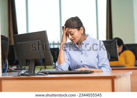 Indian woman in stress while working on computer at office. Royalty-Free Stock Photo #2344035545