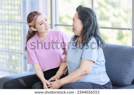 Asian senior pensioner retirement cheerful happy healthy fit mother in casual sportswear and young beautiful daughter sitting holding hands talking together after exercise working out in living room.