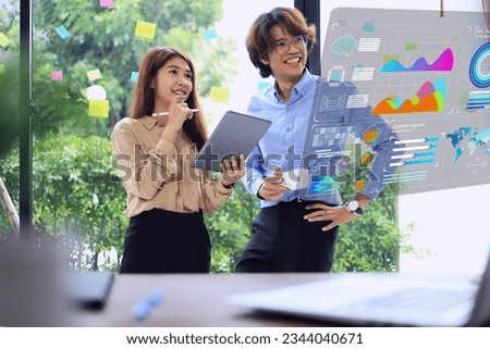 Business women and men standing and looking at business data analysis report virtual screens in their offices with happy expressions based on this month's target earnings. Data analytic dashboard.