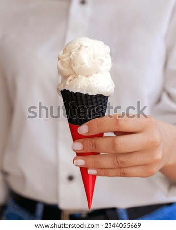 Woman's hand holds vanilla ice cream in cone