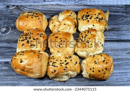 mini salty baked pastries topped with black seeds Baraka seed and stuffed with slices of alive, traditional bakeries used as snacks between the meals isolated on wooden background, selective focus Royalty-Free Stock Photo #2344075115