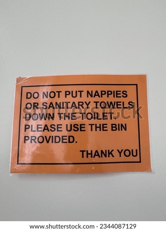 Sign do not put nappies or sanitary towels down the toilet please use the bin provided Thankyou sign on orange background