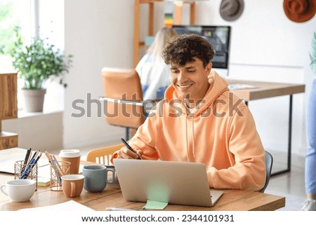 Male graphic designer working with laptop at table in office