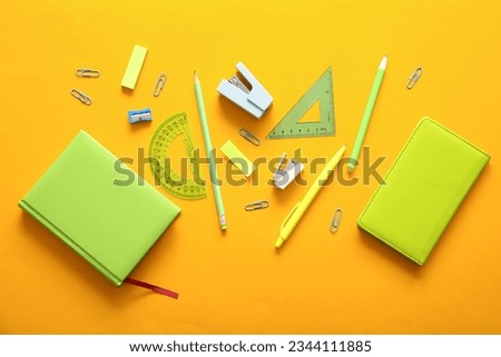 Different school stationery and notebooks on orange background
