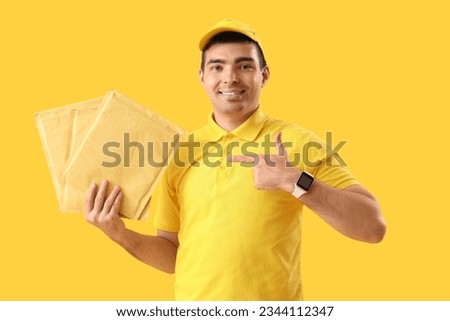 Male courier pointing at envelopes on yellow background