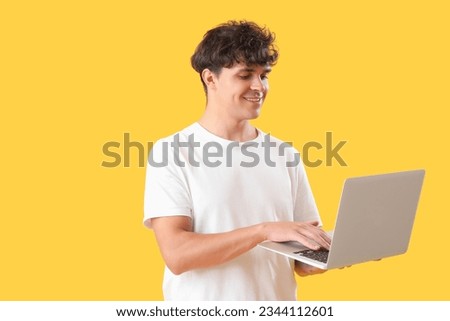 Male programmer working with laptop on yellow background