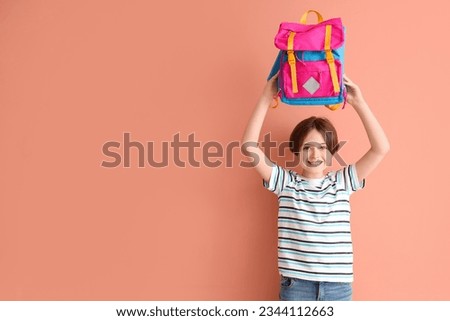 Happy little boy with backpack on color background Royalty-Free Stock Photo #2344112663