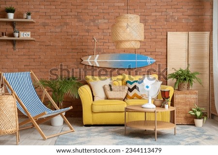Interior of stylish living room with yellow sofa, surfing board and electric fan on coffee table Royalty-Free Stock Photo #2344113479