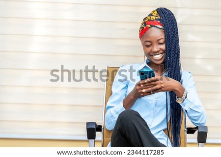 young African woman sitting in a chair, engrossed in her cell phone