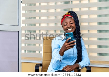 young African woman sitting in a chair, engrossed in her cell phone