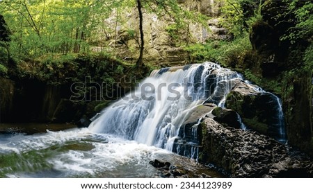 
The image you sent me shows a waterfall surrounded by rocks and greenery. The waterfall is unnamed, but it is likely a part of a larger waterfall system.