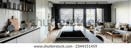 Modern composition of kitchen space with design kitchen island, black hookers, grey table, flowers, furnitures, big window and elegant personal accessories. Stylish home decor. Template.