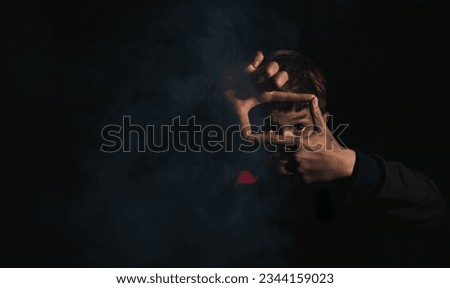 A little boy is sitting by a smoking fire in the dark