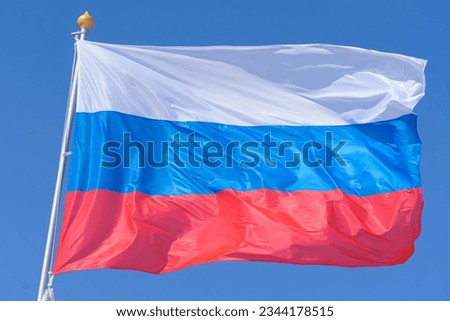 The Russian flag flutters in the wind against the blue sky