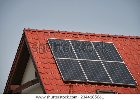 a red roof with a solar panel on it. concept of environmental conservation and sustainable energy sources.