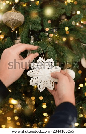 Hands that decorate the Christmas tree. Happy new year. Christmas card banner with decorative paper snowflake, bokeh lights. Mockup.