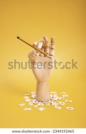 Wooden hand with pencil and wooden letters. High quality photo Royalty-Free Stock Photo #2344192465