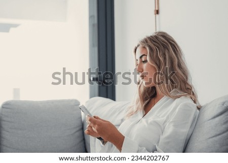 Portrait of one young attractive blonde woman using phone cell on couch relaxing surfing the net at home. Relaxing online concept lifestyle